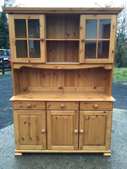 A pine dresser with moulded cornice above two glazed...