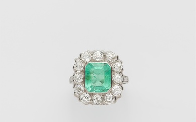 An Art Déco platinum iridium diamond and emerald cluster ring.