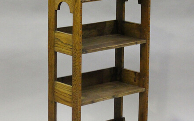 An early 20th century Arts and Crafts style oak open bookcase with a stop-fluted frieze and arched o