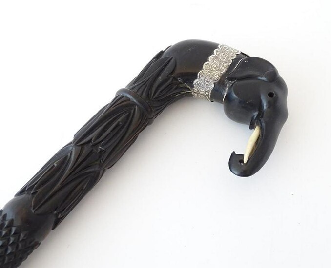 An ebonised walking stick / cane with carved detail and