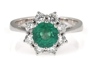 An emerald and diamond ring set with a circular-cut emerald encircled by...