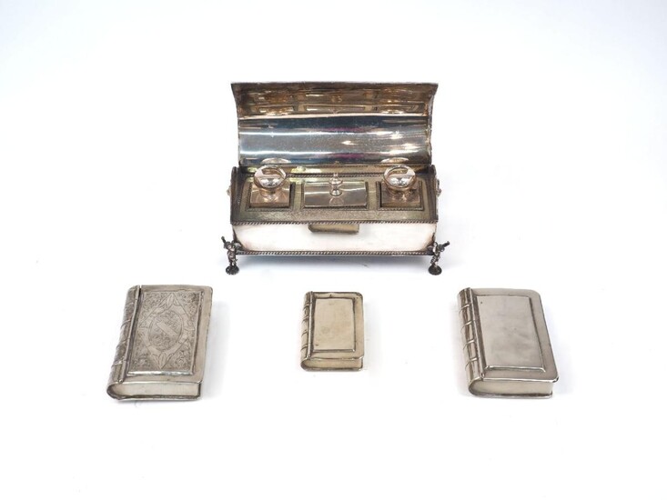 Three boxes modelled as books, white metal, apparently unmarked, designed with hinged lids and realistically banded spines, one with decorative engraving to cover, together with a Victorian silver plated desk stand, the domed lid opening to reveal...