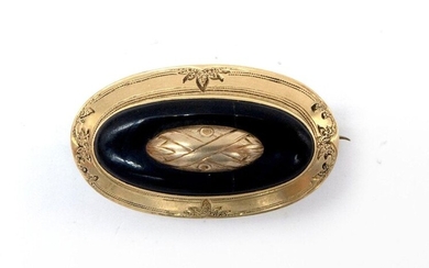 18K yellow gold brooch (metal pin), oval in shape, it holds an onyx cabochon. Engraved with a plant motif around the circumference. Dimensions : 3.8 x 2.6 cm. Gross weight : 6.94 gr. A gold, steel and onyx brooch.
