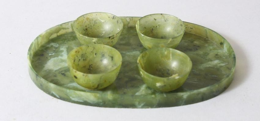 A CHINESE MOTTLED GREEN JADE OVAL TRAY AND FOUR TEA