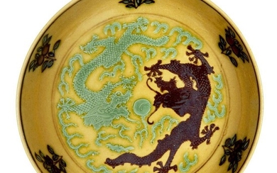 A Chinese small yellow-ground aubergine and green-decorated porcelain saucer dish, Guangxu mark and of the period, incised to the interior with two dragons amongst flames in pursuit of the flaming pearl, painted to the exterior with two kui...