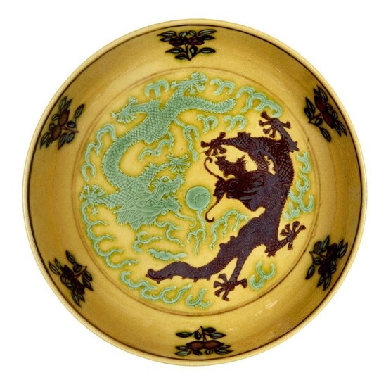 A Chinese small yellow-ground aubergine and green-decorated porcelain saucer dish, Guangxu mark and of the period, incised to the interior with two dragons amongst flames in pursuit of the flaming pearl, painted to the exterior with two kui...