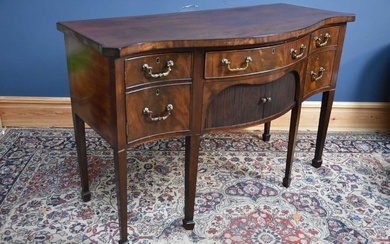 A Georgian mahogany serpentine fronted sideboard with an arrangement of...