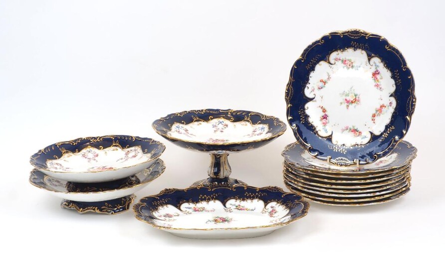 A group of Minton table wares, late 19th Century, of cream and navy blue ground with gilt scrolling highlights to scalloped rims, the centre decorated with floral swags and sprays, comprising a tazza, 12.5cm high, two footed dishes, 23.5cm...