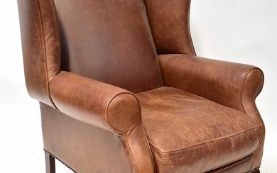 A modern brown leather wing armchair with studs, on mahogany...