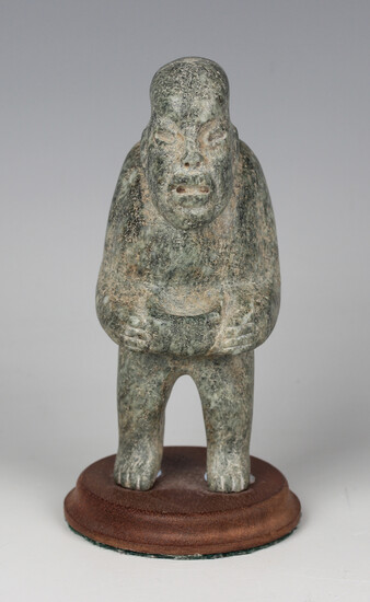 A pre-Columbian Olmec style carved green hardstone starcatcher figure, probably 900-450 BC, holding