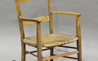 An early 20th century Arts and Crafts beech framed rocking armchair with a rush seat, height 80cm, w