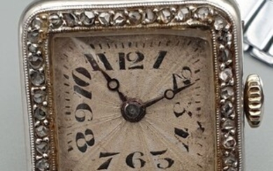 Élégante montre de dame en platine vers 1920. Boitier en platine carré, lunette sertie de...