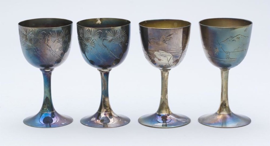 FOUR JAPANESE SILVER WINE CUPS Two with a pine tree design, one with a bird and grasses design, and one with a lake and mountain des...