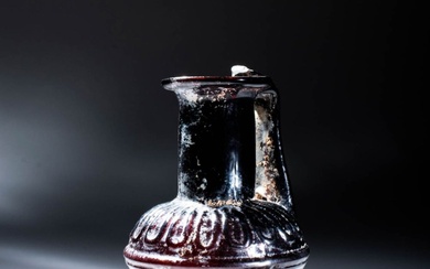 LATE ROMAN PURPLE GLASS BOTTLE DECORATED WITH MOULDED GEOMETRIC MOTIF