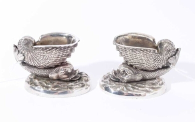Pair of 19th century cast white metal salts in the form of a nautilus shell on the back of a dolphin, on a wave pattern oval base, possibly an Elkington electrotype, 9.5cm overall width