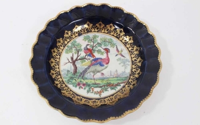 Worcester plate, circa 1770, of fluted form, polychrome painted with exotic birds, on a cobalt blue and gilt-patterned ground, seal mark to base, 19cm diameter