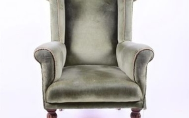 A late Victorian green-upholstered wing back armchair on turned legs terminating in brass castors, 65 cm wide.