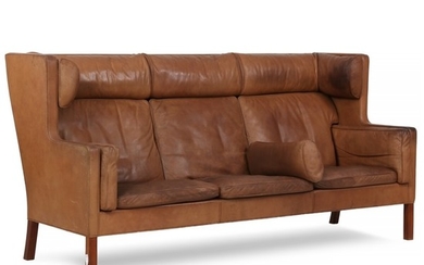Børge Mogensen: “Kupé”. Three seater sofa with nut wood legs. Upholstered with brown coloured leather. H. 107 cm. L. 216 cm. D. 86 cm.