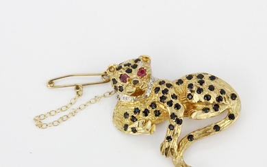 A 9ct yellow gold leopard brooch set with sapphires, diamonds and ruby eyes, L. 3.7cm.