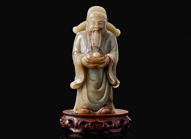 A Chinese carved celadon jade figure of a civil deity, possibly Caishen 青玉雕