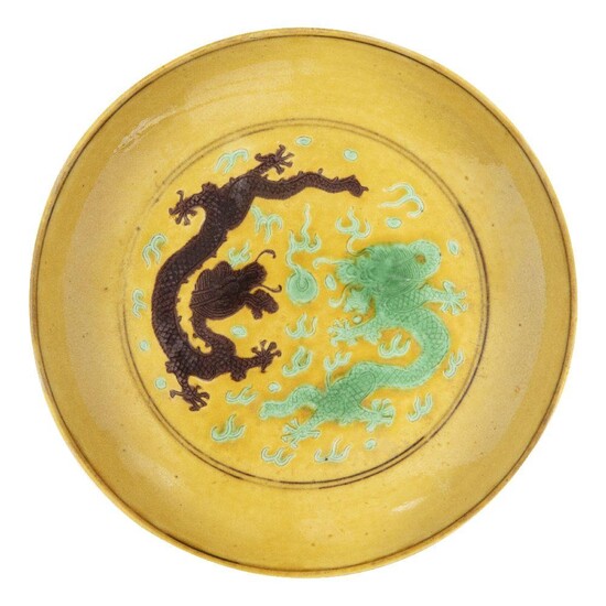 A Chinese imperial porcelain saucer dish, Tongzhi mark and of the period, painted in green and aubergine enamels with two five-clawed dragons encircling a flaming pearl amongst stylised clouds and flames, the underside painted with aubergine grapes...