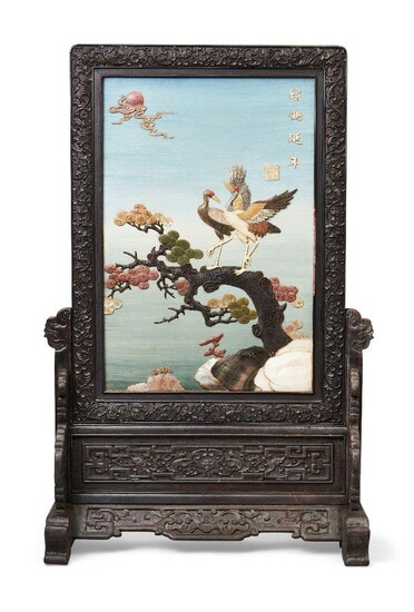 A Chinese lacquered and inlaid hardwood table screen, 20th century, applied to one side with a pair of cranes on pine, inlaid with soapstone, coloured hardstone, bone and hardwood, bearing an apocryphal Qianlong mark next to inscription, the...