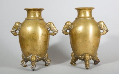 A PAIR OF CHINESE BRONZE 'ELEPHANT' VASES. Qing Dynasty. The high globular body of each with set with a lipped waisted neck with an everted rim, the shoulders set with twin elephant heads, supported on three equally spaced elephant head feet, around a...