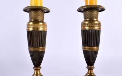 A PAIR OF EARLY 19TH CENTURY FRENCH EMPIRE TWO TONE BRONZE CANDLESTICKS formed as tapered ribbed col