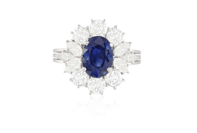 A SAPPHIRE AND DIAMOND CLUSTER RING The oval-shaped...