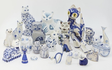 A collection of pottery cats, of blue and white colour way, to include; a David Sharp Rye Pottery seated cat, with painted signature, 18.5cm high, 19cm wide, a faience cat painted with birds and flowers, unmarked, 15cm high, a pair of terracotta...