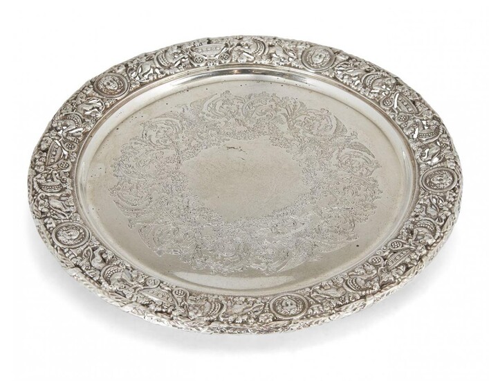 A decorative silver serving plate, London, c.1920, Mappin & Webb, the pierced rim richly decorated with lions, urns and masks to a flat base engraved with foliate and eagle design wreath, the plate raised on three bracket feet, 27.5cm dia., approx...