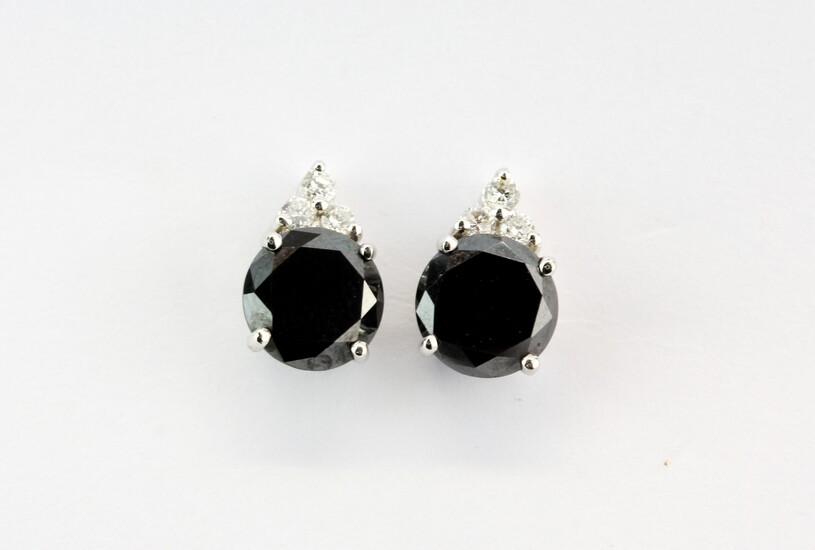A pair of 18ct white gold stud earrings set with round cut black diamonds, approx. 3.3ct overall, and three brilliant cut diamonds, L. 1cm.