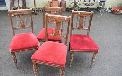 A set of four Victorian oak dining chairs having rail and spindle back, over stuffed seats on turned