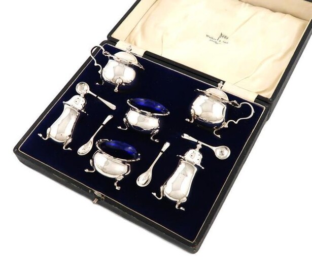 A six-piece silver condiment set, by Walker and Hall, Birmingham 1932, circular bellied form, wavy-edge border, on three hoof feet, comprising: a pair of mustard pots, a pair of pepper pots, and a pair of salt cellars, with blue glass liners and four...