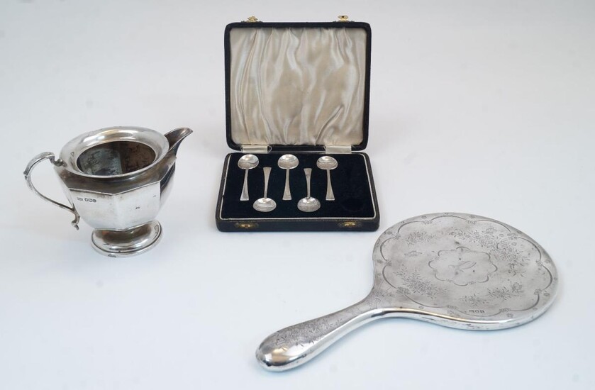 A small group of silver, comprising: a Mappin & Webb milk jug, Sheffield, 1925, 9.6cm high; a cased part-set of coffee spoons, Birmingham, 1934, William Suckling Ltd, with five spoons; and a silver mounted hand mirror, London, 1911, rubbed maker's...