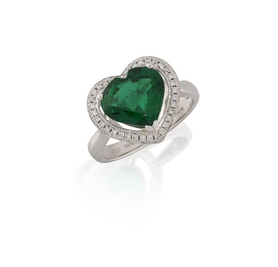 An emerald and diamond ring, the heart-shaped emerald, weighing approximately 2.89 carats, in raised claw mount to a brilliant-cut diamond surround, approximate total weight of diamonds 0.25 carats, mounted in 18ct white gold, Birmingham hallmarks...