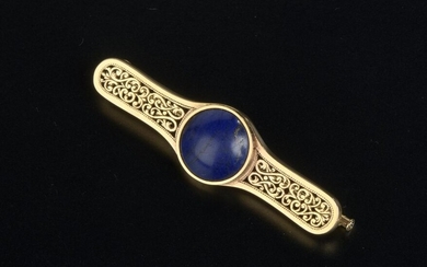 Bar brooch in 18k yellow gold, decorated with openwork scrolls, centered on a lapis lazuli cabochon.