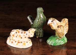Three Pottery Animals; A 19th century green glazed red clay bird whistle, 4 in (10 cm) in height, a late 18th century style sponge-glazed squirrel 3½ in (9 cm), and a creamware figure of reclining lamb on an oval base with crimped edge, 2¼ in (6
