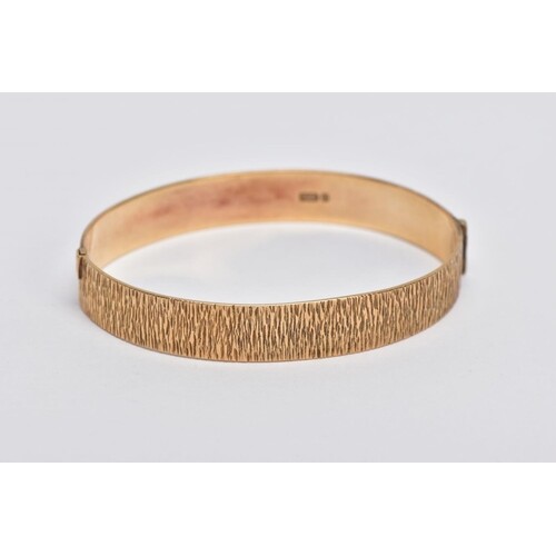 A 9CT GOLD HINGED BANGLE, bark texture to the full bangle, t...