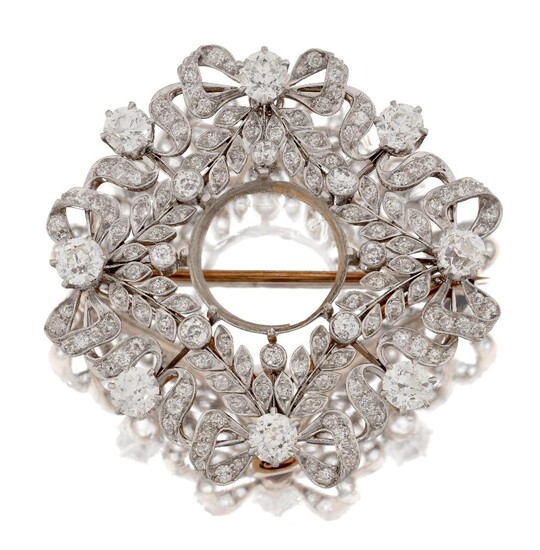 A Belle Epoque, gold and platinum diamond brooch, centre stone deficient, of ribbon and garland design, set throughout with old brilliant-cut diamonds, with ribbon bow surmounts and claw-set diamond cardinal points, centre stone deficient, c.1915...