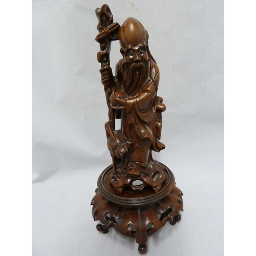 A Chinese bamboo root carving of an immortal holding a staff...