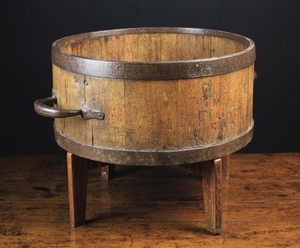 A George IV Coopered Oak Bushel Grain Measure on a later stand. The cylindrical iron bound vessel fitted with carrying handles either side, and stamped repeatedly with a crown, Co. Ross and initials M.L., 9 in (23 cm) high, 16½ in (42 cm) including