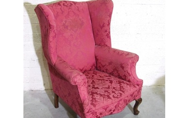A Georgian-style upholstered wing armchair with shaped wings...
