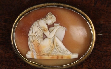 A Victorian Carved Shell Cameo Brooch finely carved with a classical female figure sat with amphora.