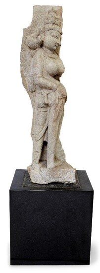 A sandstone Aspara (celestial deity), Central India, Probably Madhya Pradesh, 10th-11th century, depicted with her right hand placed upon her hip, wearing a diaphanous robe with trailing scarves, extensive jewellery and a multi-stranded belt; with...