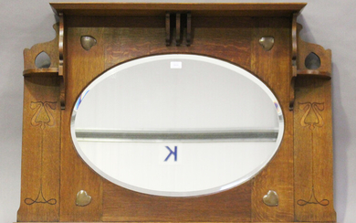 An Edwardian Arts and Crafts oak overmantel mirror, in the manner of Shapland & Petter, the oval