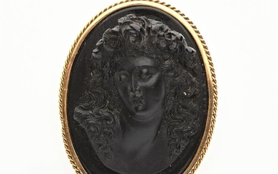 BROCHE en or jaune 750/°°torsadé ornée d'une plaque de basalte collée sur onyx figurant un buste de femme les cheveux ondulés couronnée de fleurettes. Travail italien, fin XIXème siècle. H. : 5 cm. PB : 43,3 g.