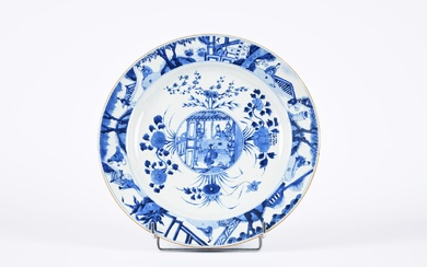 Chine, période Kangxi (1662-1722). Plat en porcelaine bleu-blanc, à décor de dignitaires dans un pavillon,...