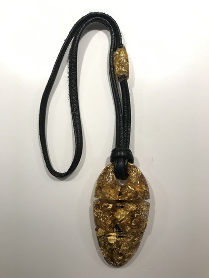 Gerda Lynggaard: An acrylic pendant with gold leaf, mounted on black leather string. For Monies. L. 60 cm.