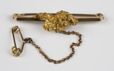 A 9ct gold bar brooch, mounted with a gold nugget, fitted with a safety chain, Birmingham 1934, weig